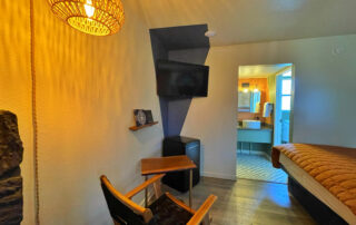 Cozy amenities at The Club, including chair, side table, fridge, flatscreen TV, and a reading nook.