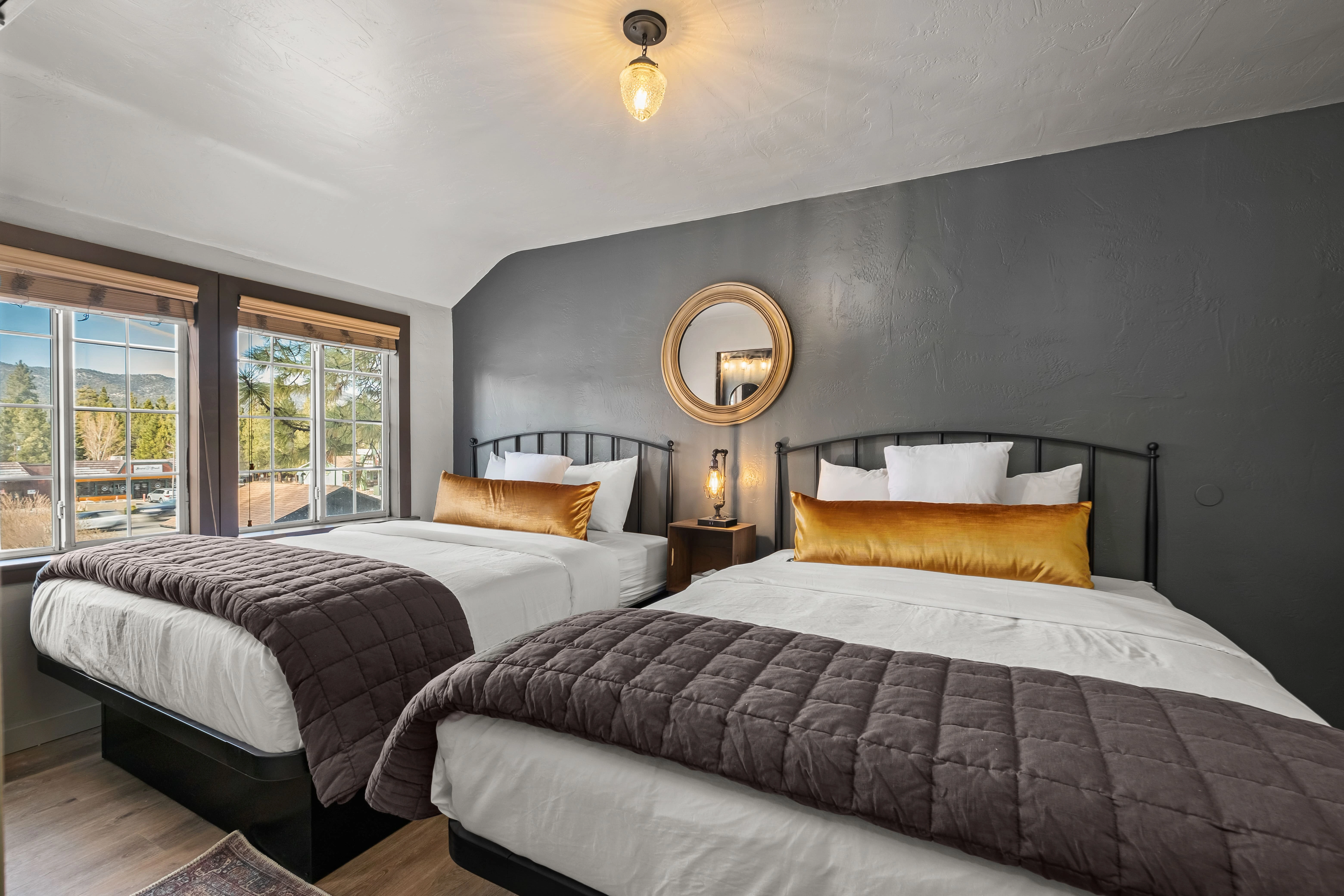 A hotel room with two twin beds, a window, and a mirror