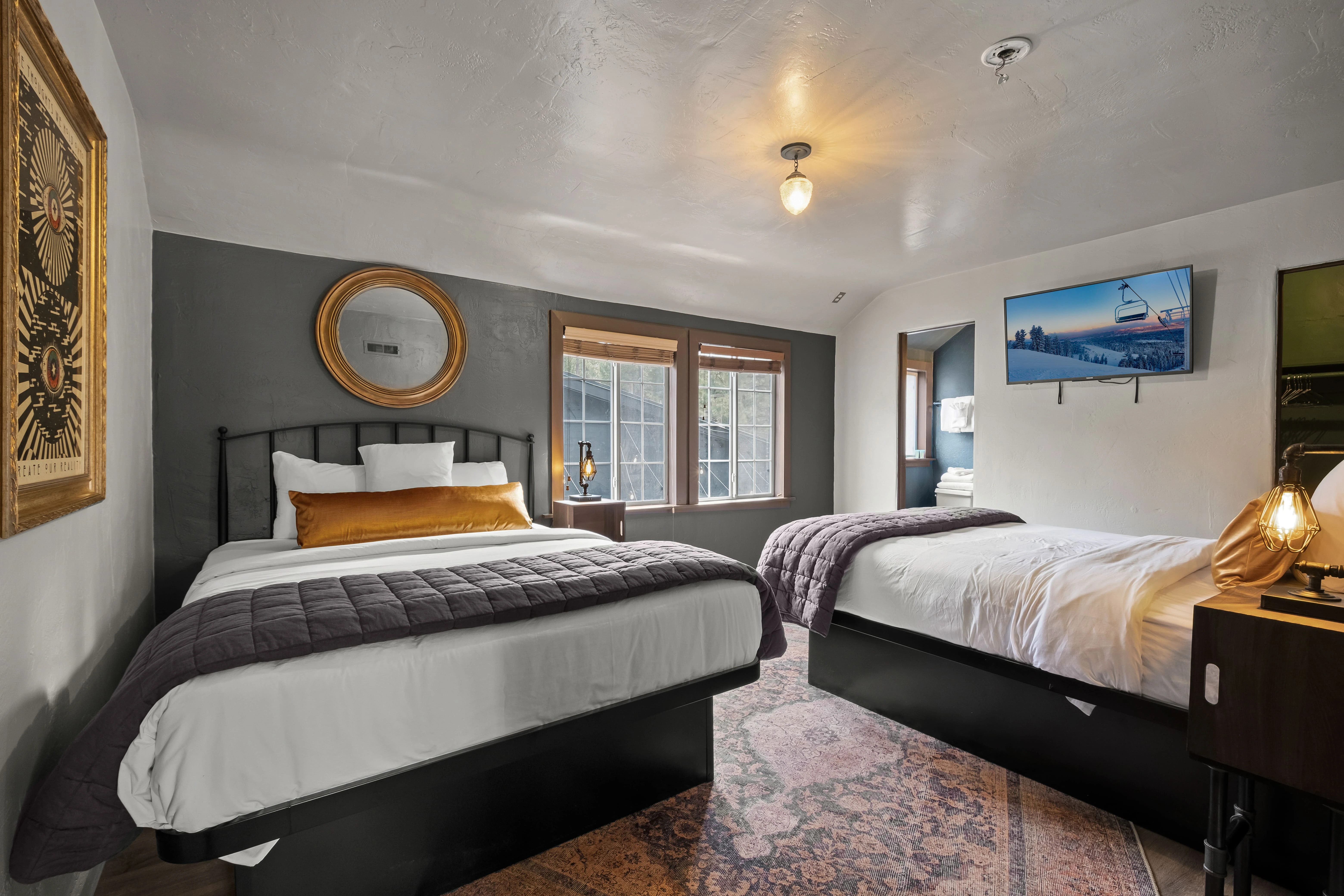A hotel room with two beds, a flat-screen TV, and a window.