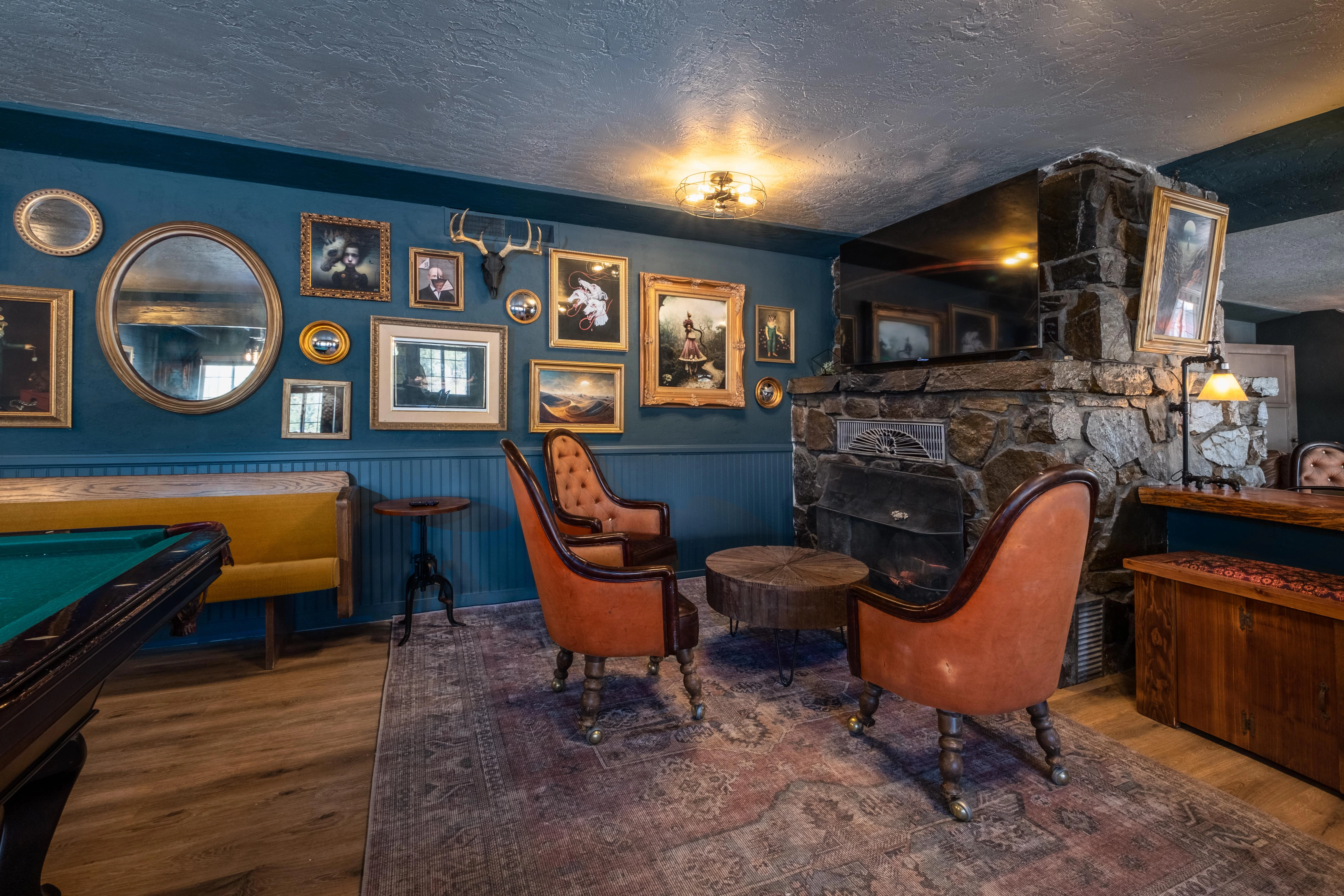 A cozy lounge area with a stone fireplace, pool table, and comfortable seating.