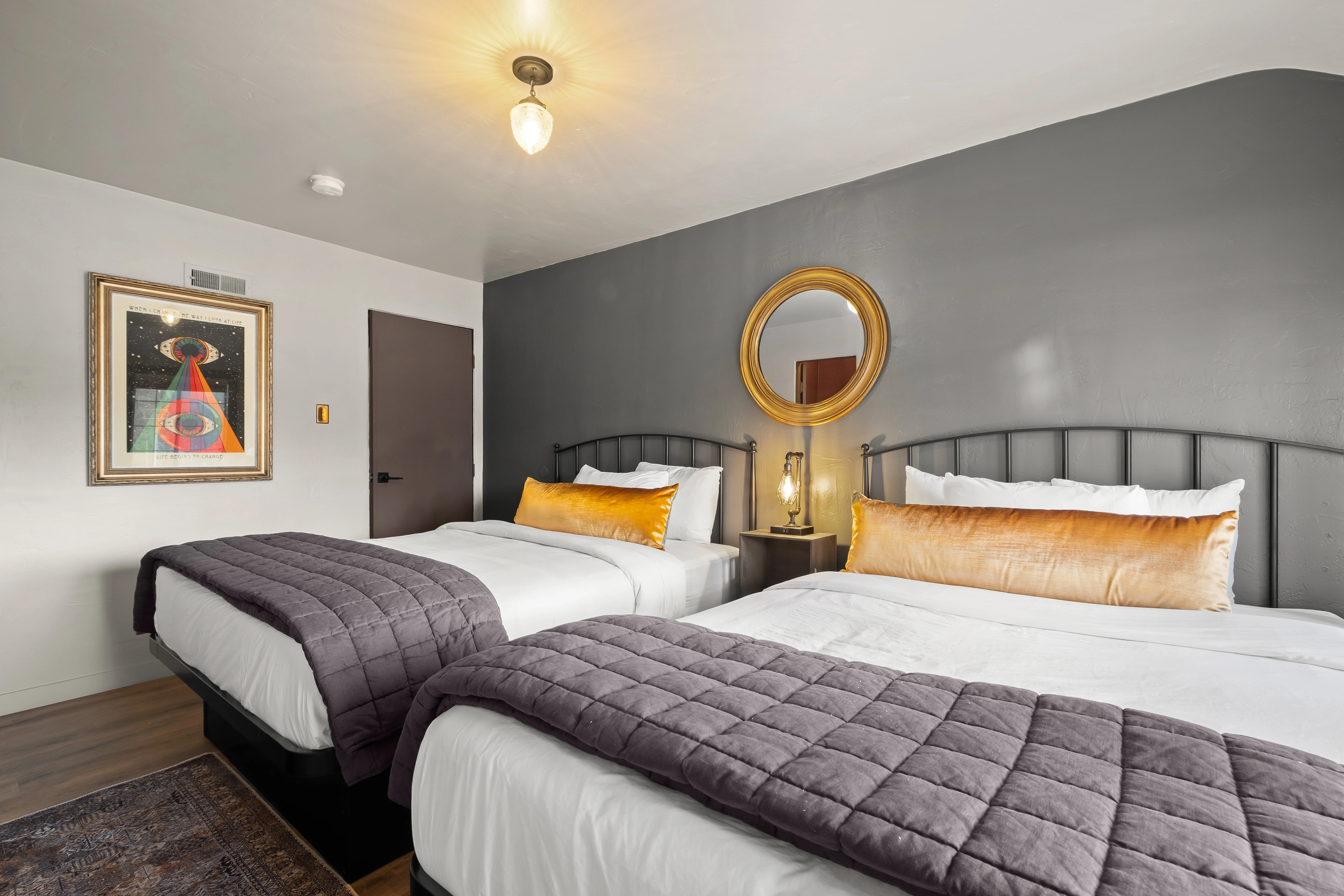 A hotel room with two beds, a nightstand, and artwork on the wall.