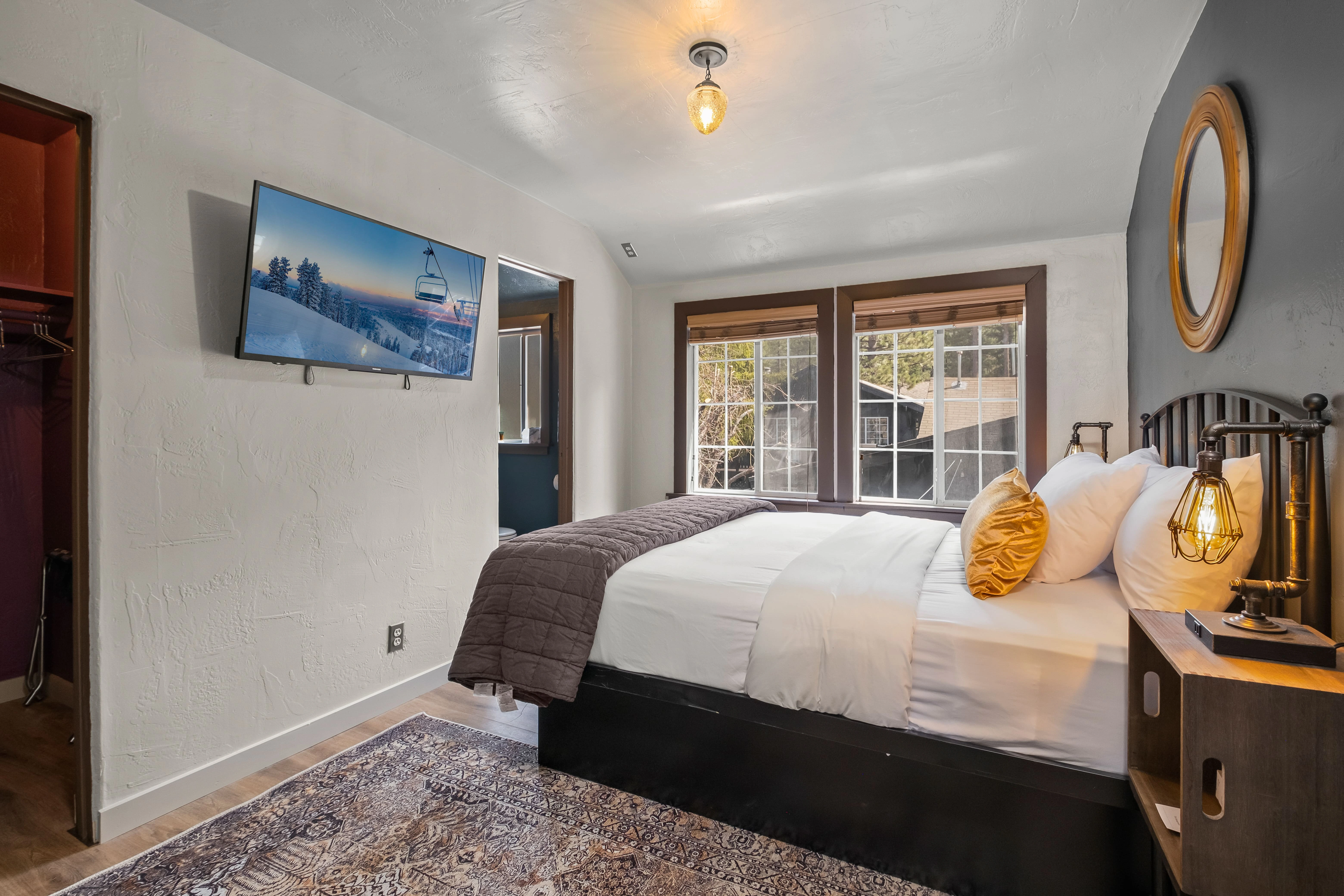 A hotel room with a large bed, flat screen TV, and window