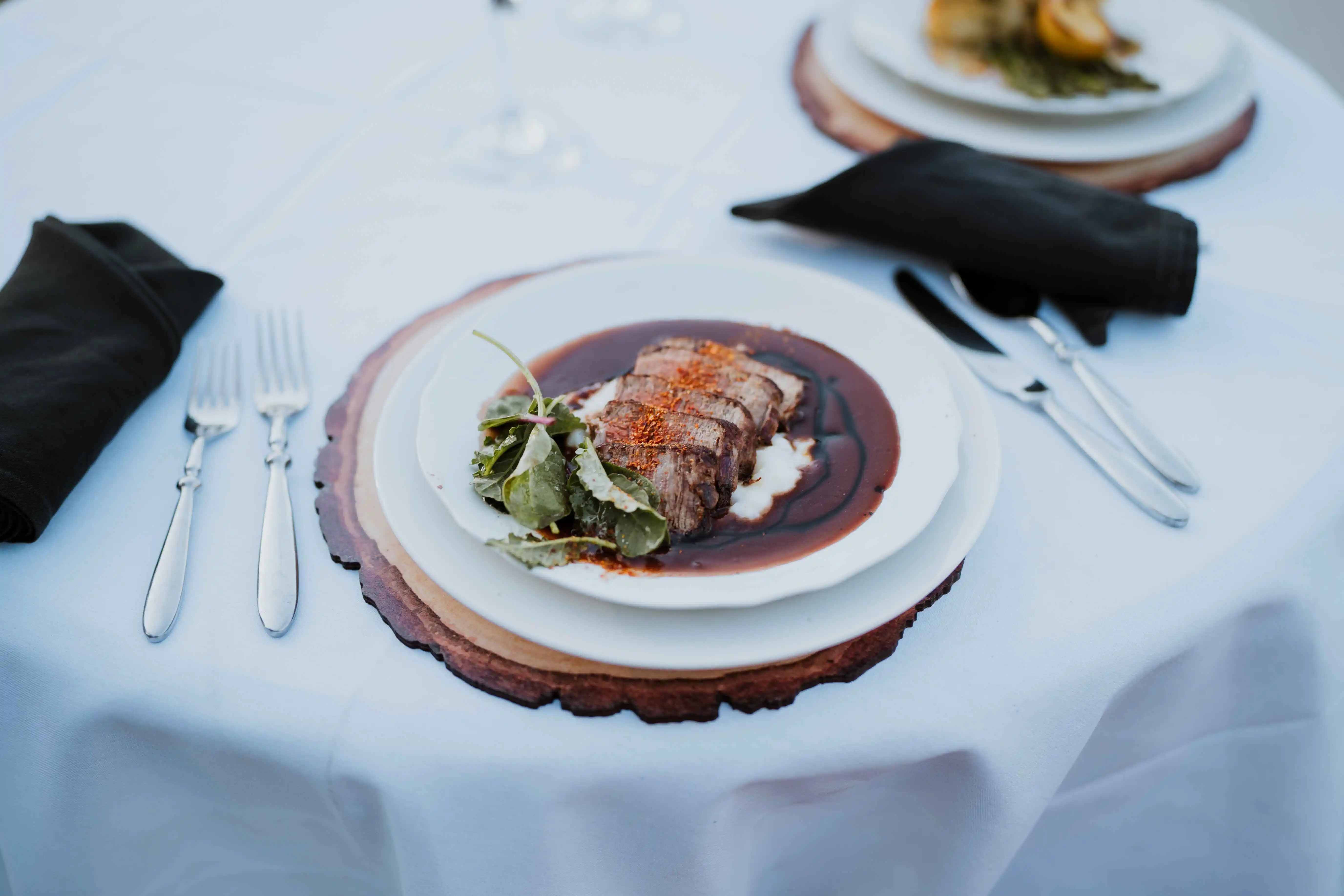 A fine dining table setting with a plate of food.