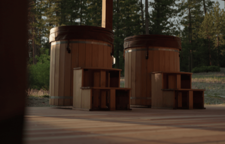 Two wooden hot tubs on a deck in an outdoor setting with trees in the background.