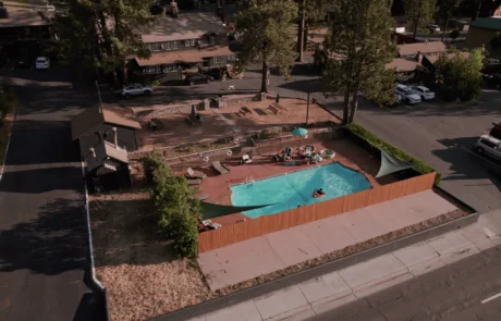 Aerial view of a fenced pool area with lounge chairs and trees.