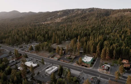An aerial view of a small town surrounded by trees and mountains.